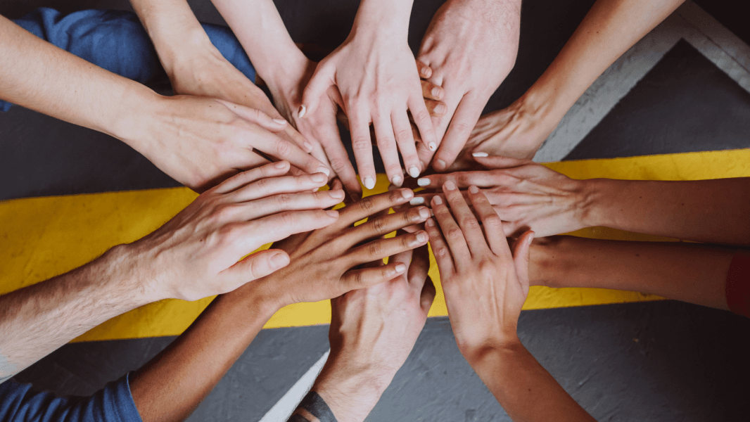 Many hands stacked together in a circle as a sign of teamwork.